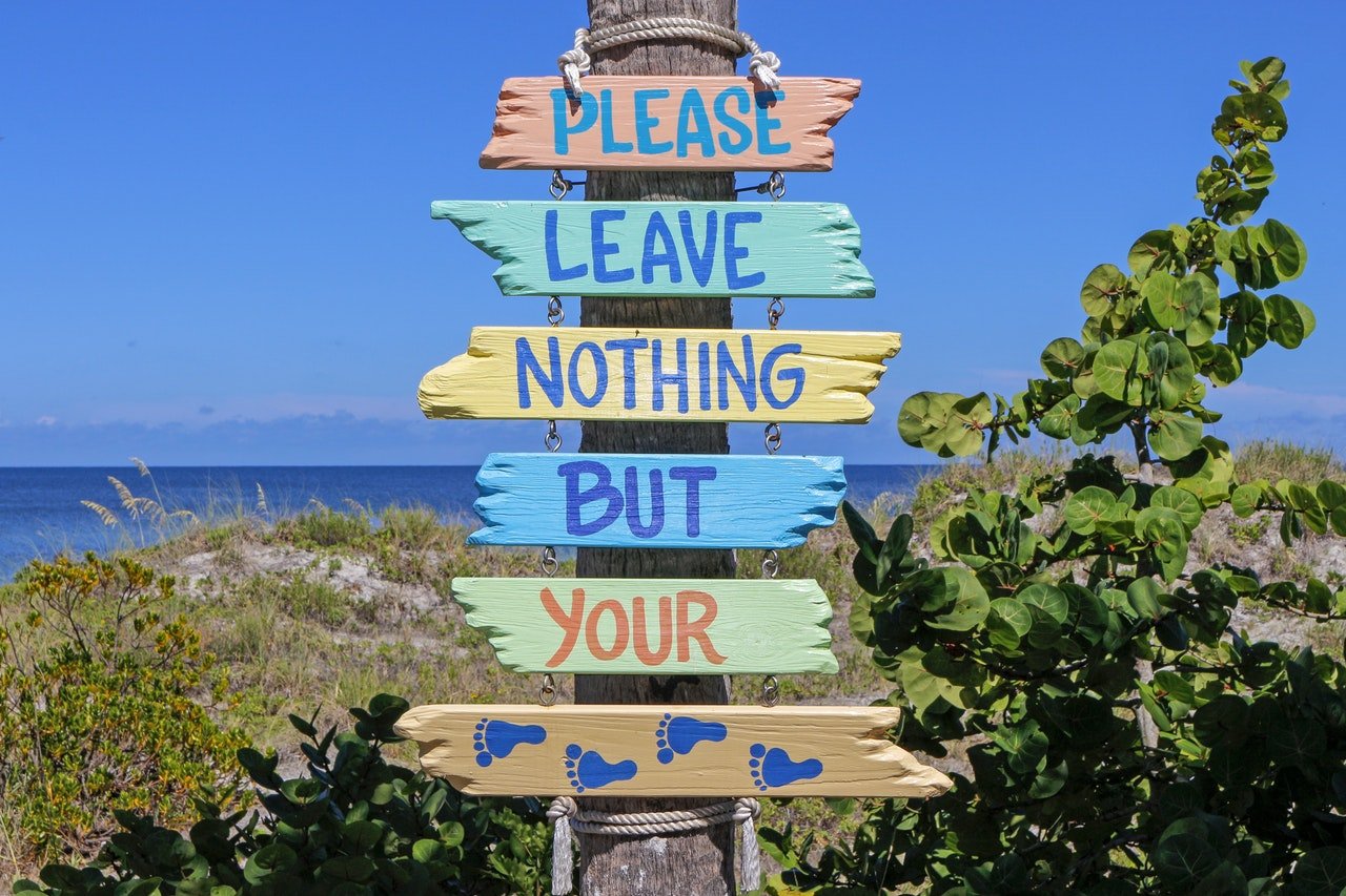 Please Leave Nothing But Your Footprints sign by beach