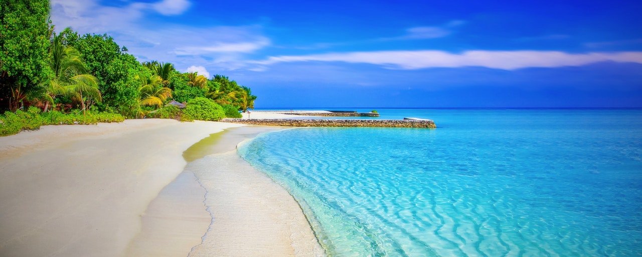 A picture of a stunning empty beach with clear water and blue skies.