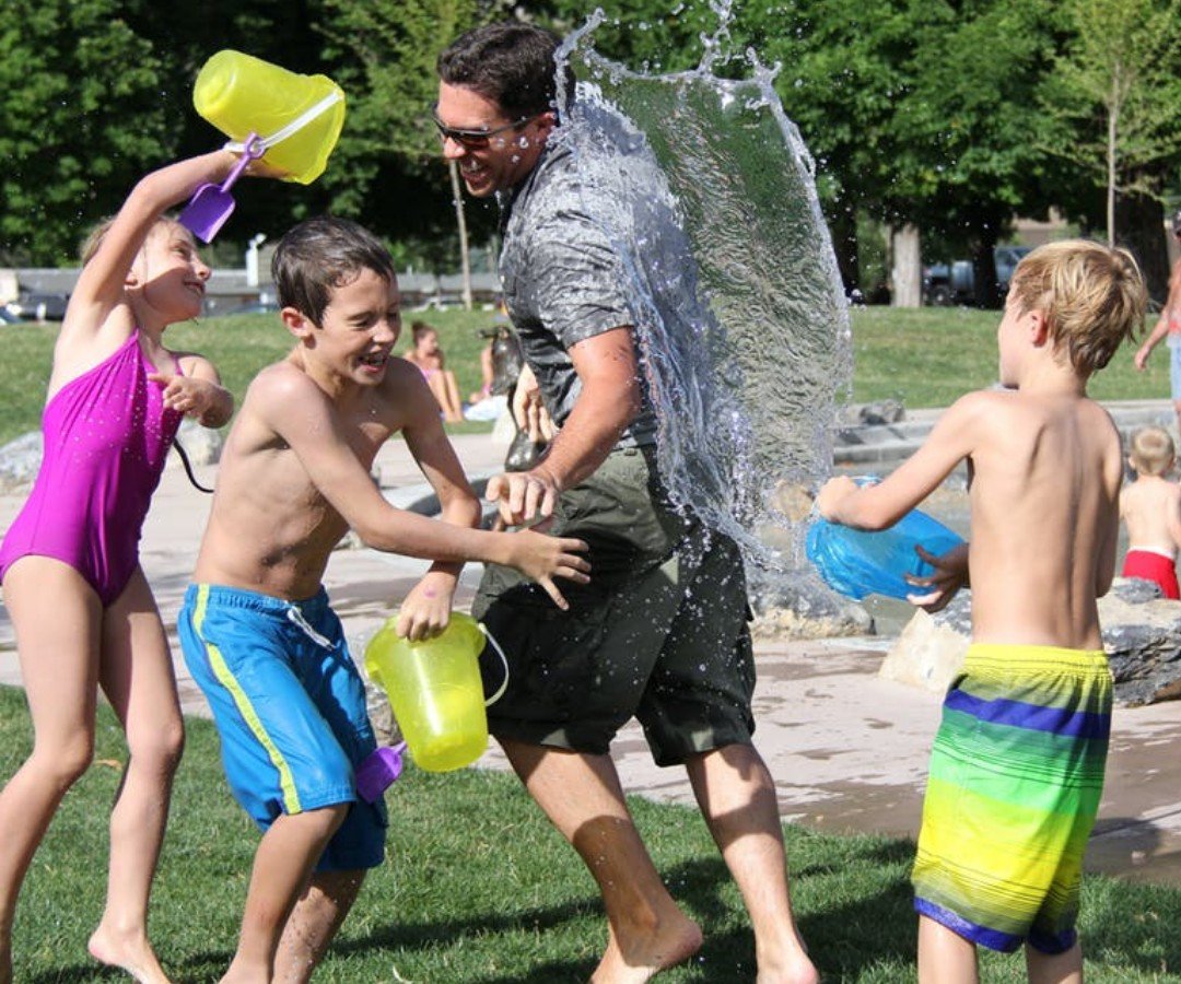 Photo of a happy laughing family having a water fight with buckets of water