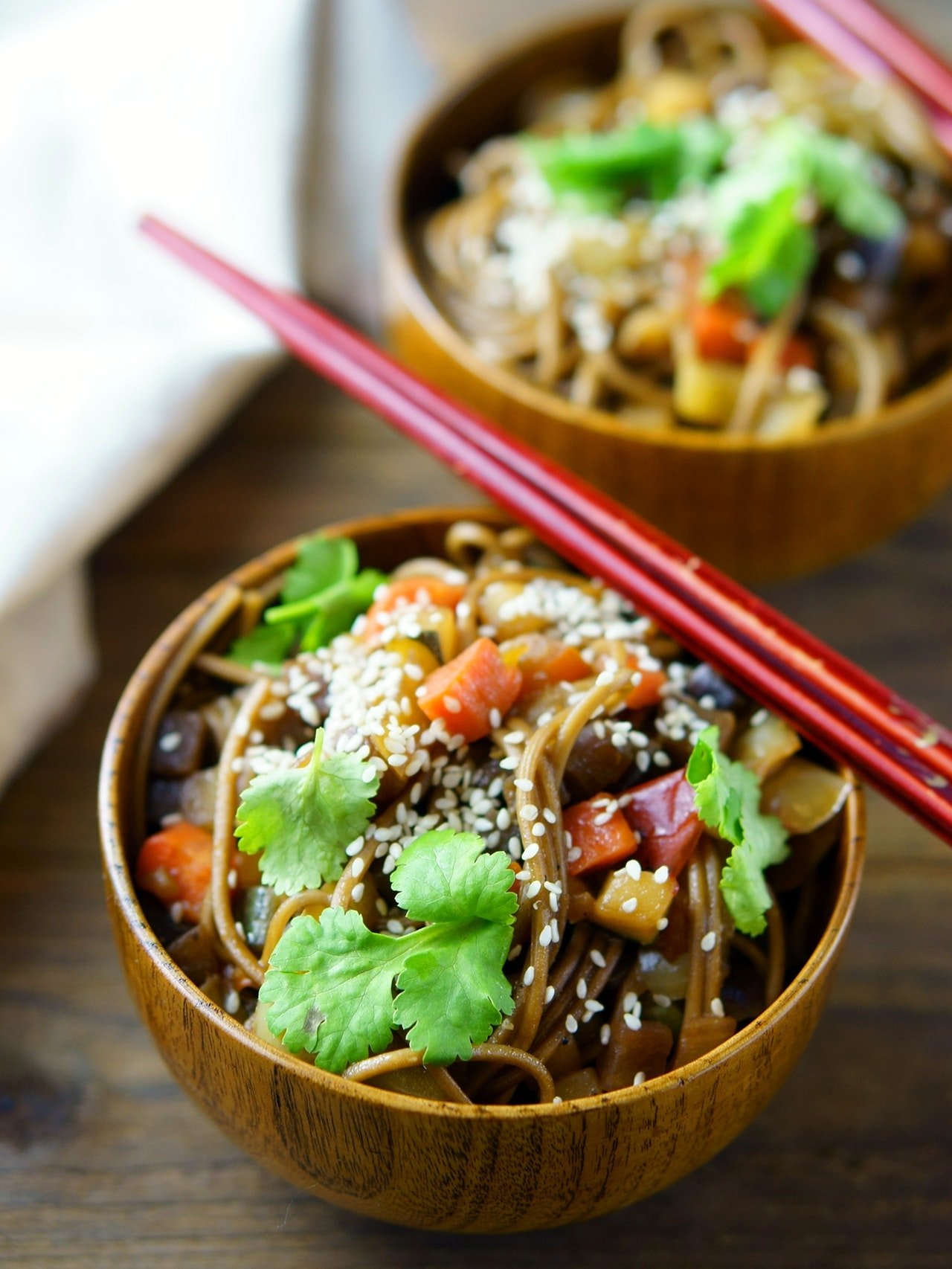 Delicious noodle dish in a wooden bowl with chopsticks