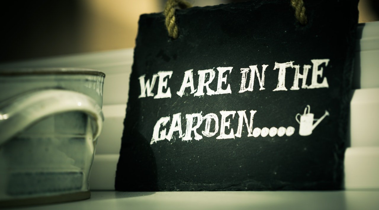 Sign saying we are in the garden. Watering can to edge of picture.