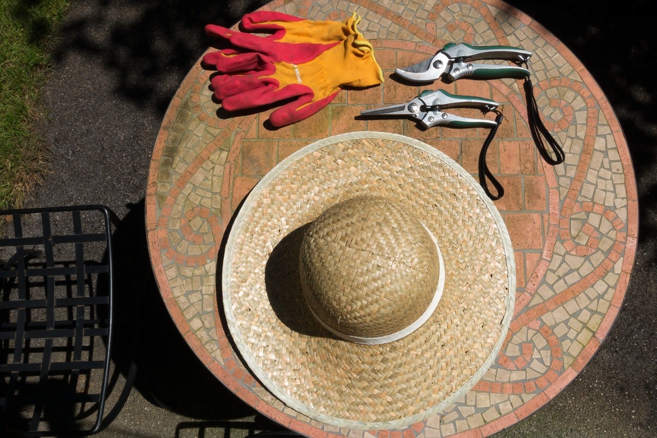 A flatlay picture of gardening gloves, hat and pruning shears