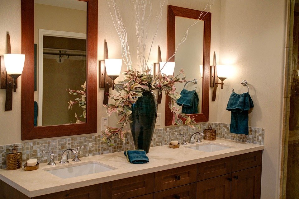 Double sink in bathroom. Large mirrors. Bathroom accessories. Large vase of flowers in centre