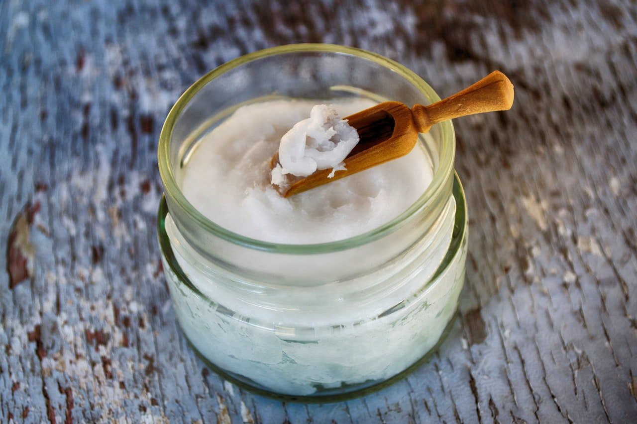 Coconut oil in glass jar with wooden scoop