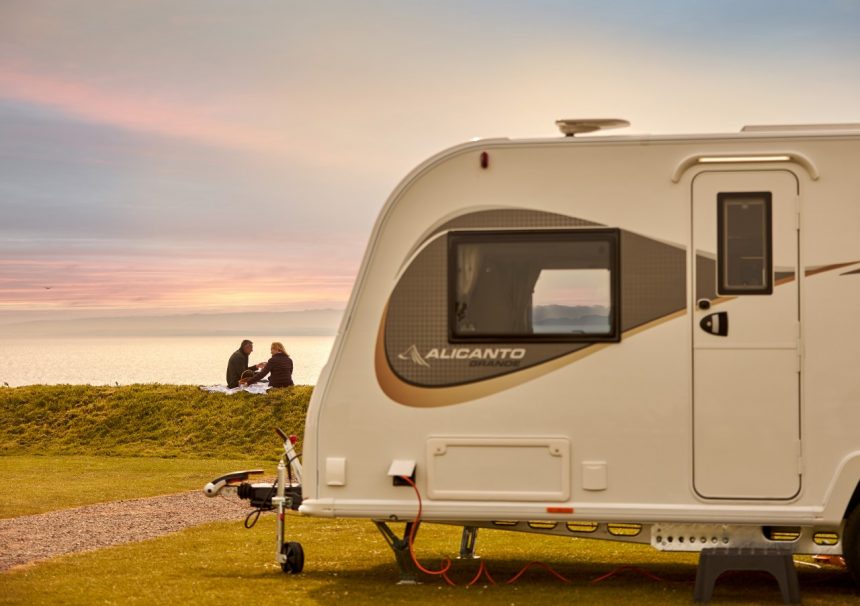 Campbells Caravans - Alicanto Grande caravan in forefront, couple at sunset in background