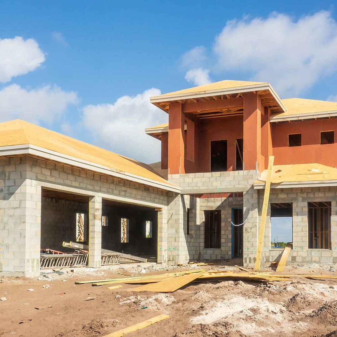 A residential building made of wood and bricks surrounded by a dirt yard that’s in the middle of construction.