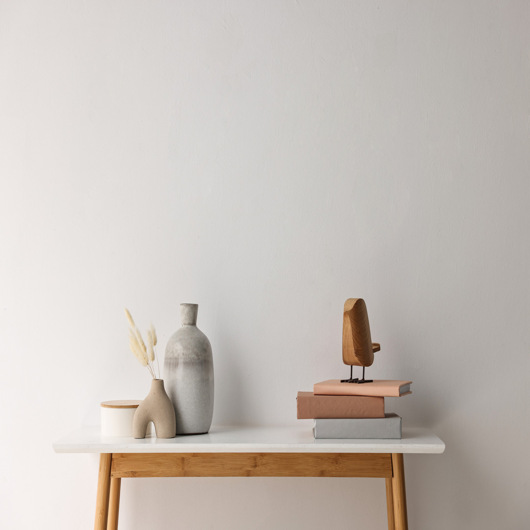 A minimally styled console shelf in a wooden material with a neutral colored wall behind it. The decor is simple.