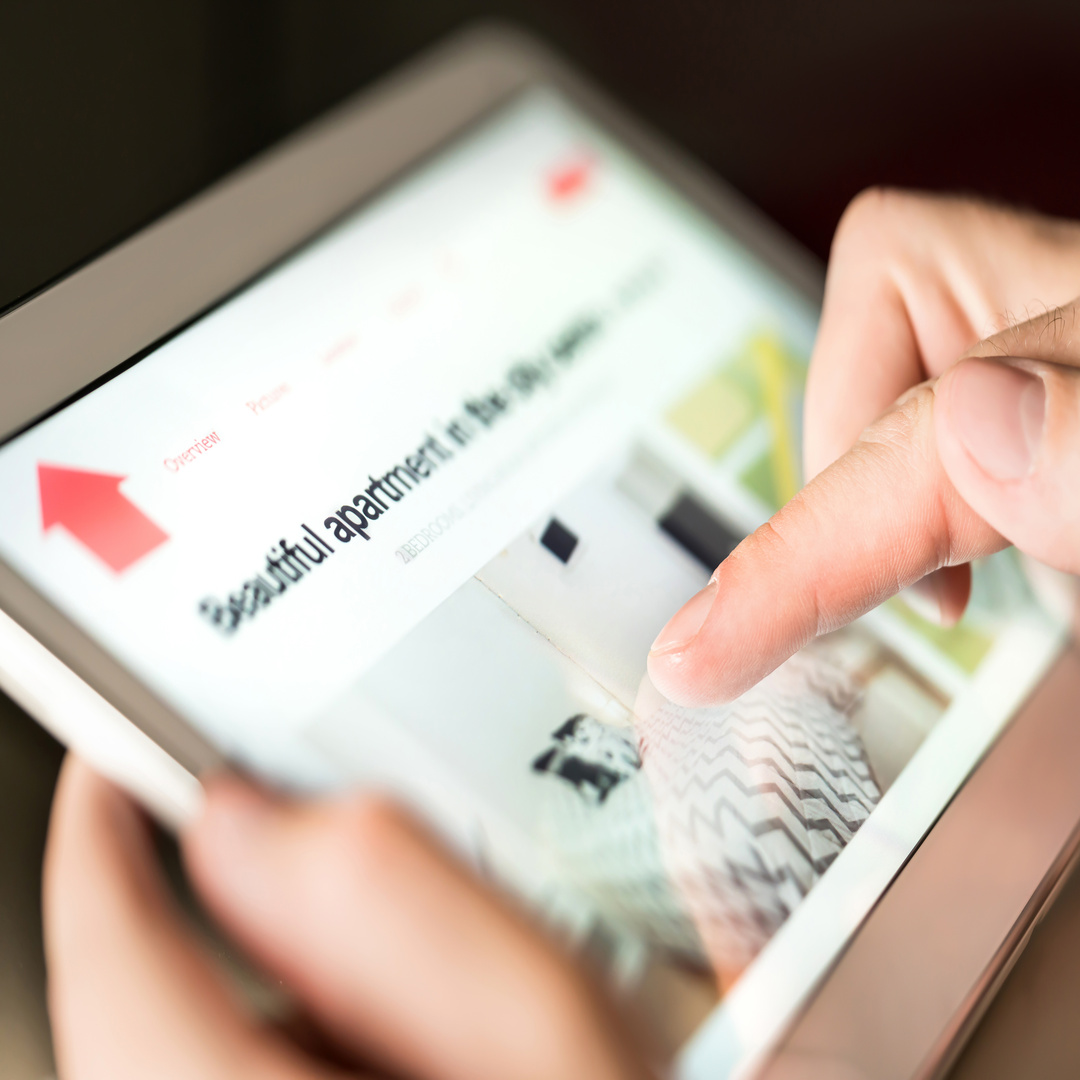 A close-up of a person using a tablet to search rental listings on an app that says "Beautiful apartment" at the top.