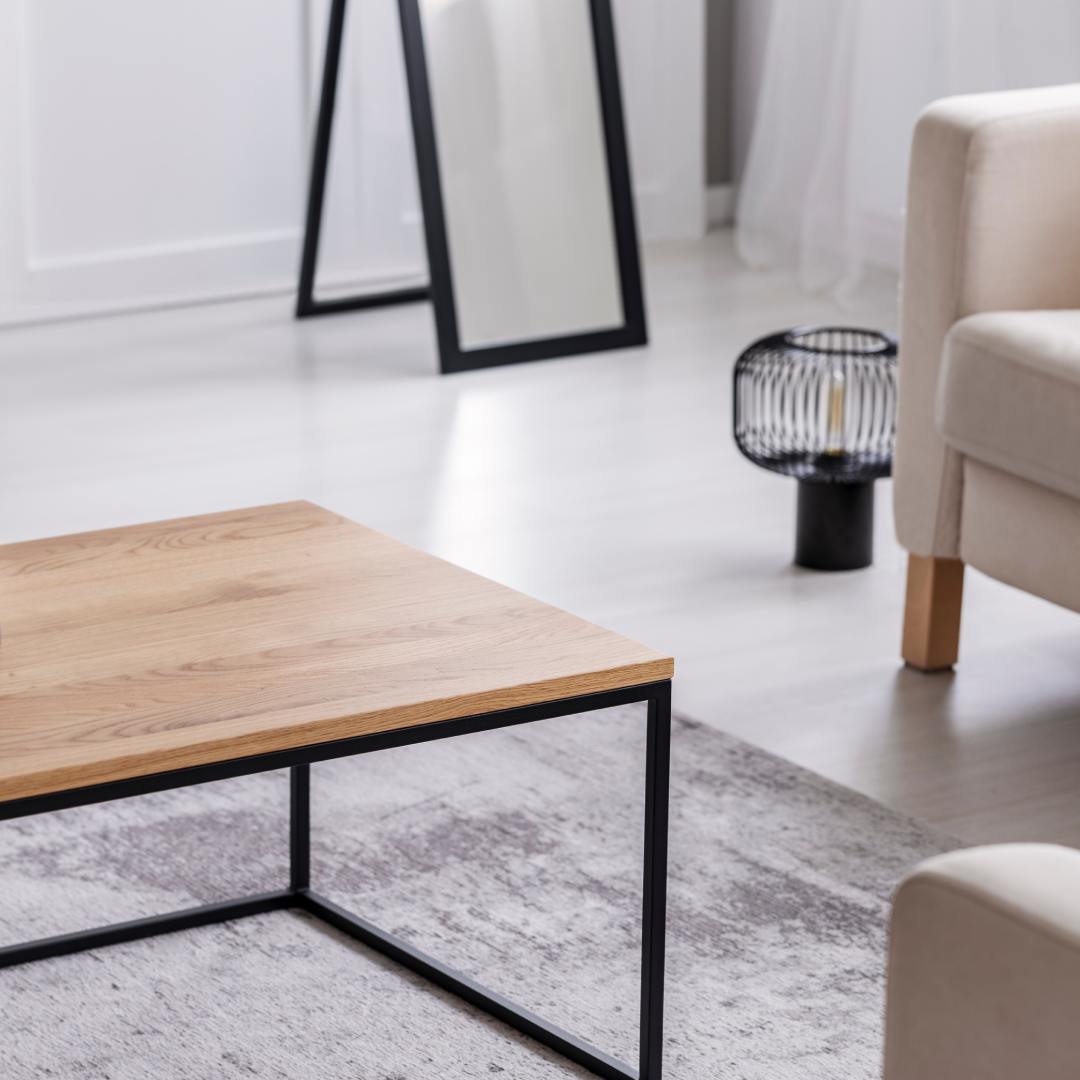 A close-up of a living room area with gray furniture and a coffee table in the center with black legs.